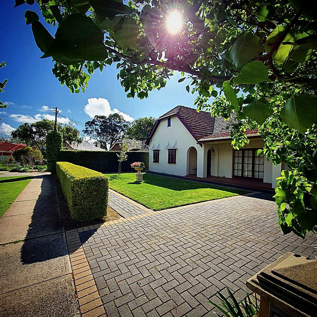 Character home with manicured hedge, lawn and paved driveway