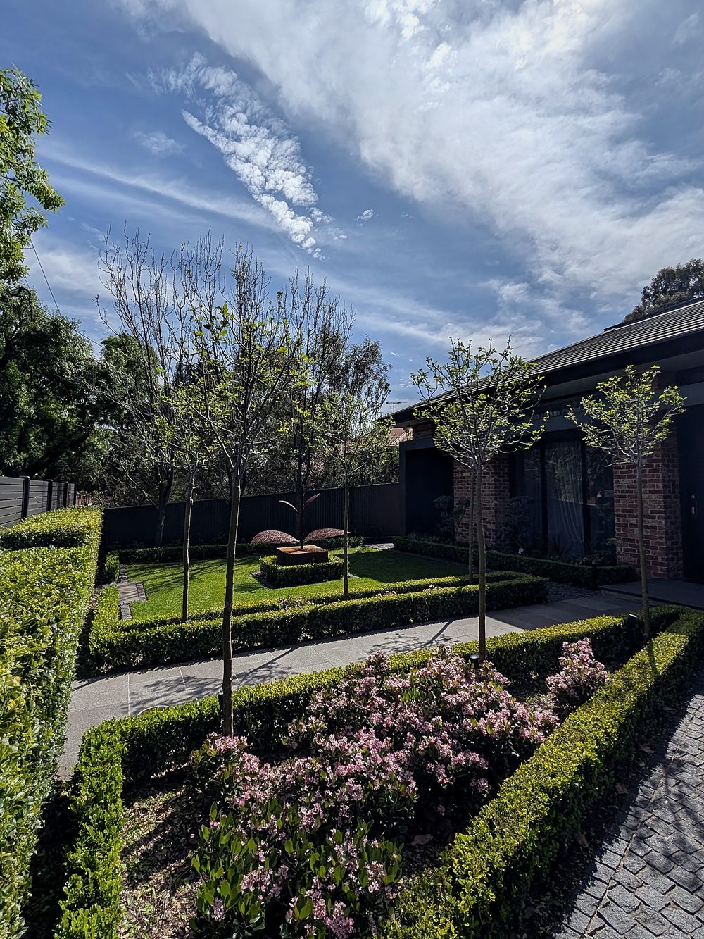 Formal designer garden with clipped box hedges, standard trees and flowering shrubs