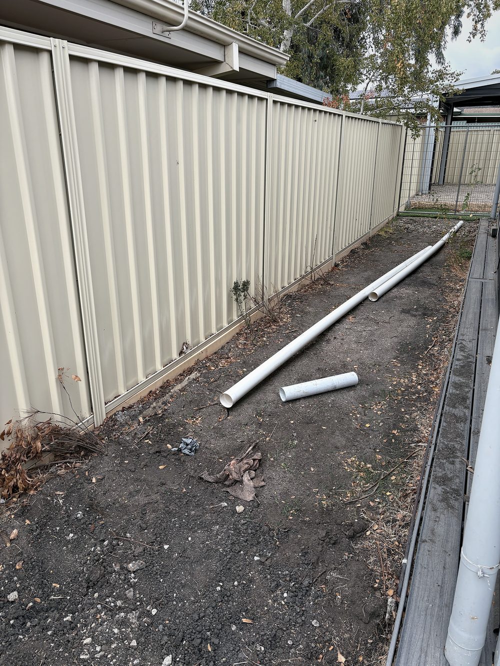 The side strip before — bare dirt, weeds and debris